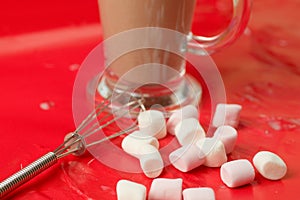 Beautiful shot of a glass of chocolate milkshake and marshmallows on a red table