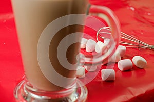 Beautiful shot of a glass of chocolate milkshake and marshmallows on a red table