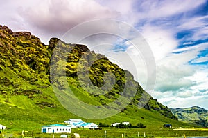 Beautiful shot of green mountains under a bright clou sky in Iceland