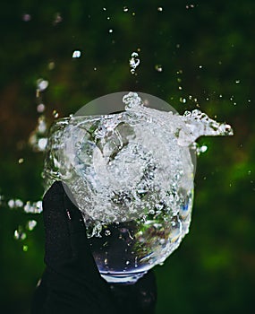 Beautiful shot of the hand holding a glass of fresh water with a splash