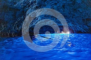 Beautiful shot of the illuminated interior of the Blue Grotto with a boat in Italy