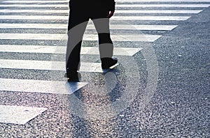 Beautiful shot of a man dressed in black crossing the street on a zebra