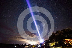 Beautiful shot of a man holding a light beam to the night sky full of stars