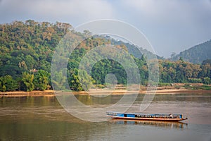 Beautiful shot of the Mekong River with a floating boat near mountains in Luang Prabang, Laos