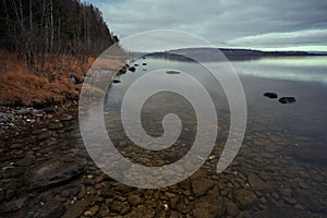 Beautiful shot of the Mjosa lake under a gloomy sky near a forest in Skreia, Toten, Norway