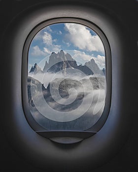 Beautiful shot of mountains and a cloudy sky from the inside of plane windows