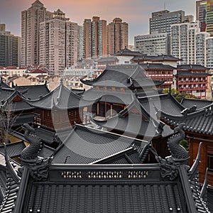 Beautiful shot of an old Buddhist temple rooftop against skyscrapers of Shanghai, China