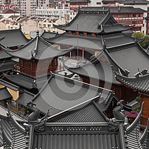 Beautiful shot of an old Buddhist temple rooftop against skyscrapers of Shanghai, China