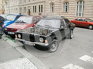 Beautiful shot of an old-fashioned black vintage car with other cars in the background on the street