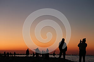 Beautiful shot of people at a seashore at sunset