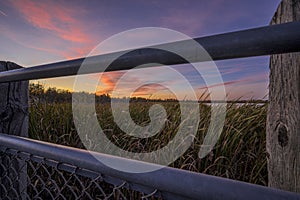 Beautiful shot of a railing near a field under a sunset sky in Grande Prairie of Alberta, Canada photo