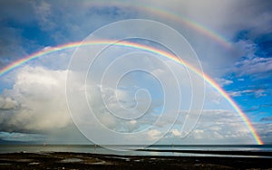 Beautiful shot of a rainbow over the sea under a blue sky
