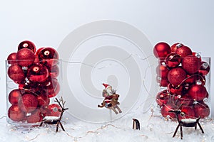 Beautiful shot of red Christmas balls in a transparent box and a small Santa toy on white background