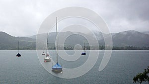 Beautiful shot of sandbagger sloop on a sea with a cloudy mountain on a gloomy day