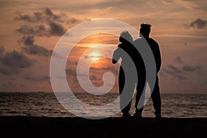 Beautiful shot of the siluette of a loving couple admiring the ocean in Guernsey at sunset