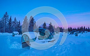 Beautiful shot of snow covering glassy igloos serving as tourist observatories.