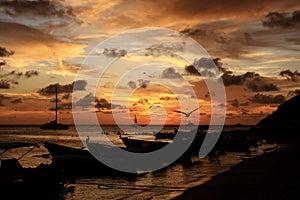 Beautiful shot of the sunset in a seashore with boats on it