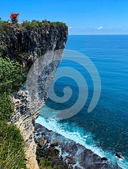 Beautiful shot of a tall cliff by the coastline with clear blue sea