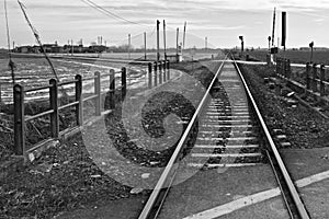 Beautiful shot of train tracks in the middle of an empty field in black and white