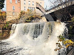 Beautiful shot of a waterfall under the bridge in front of apartment buildings during daytime