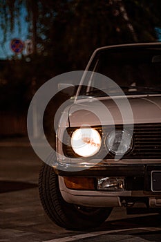 Beautiful shot of a white vintage classic car with round headlights in the street at night