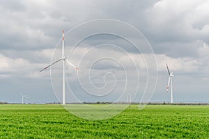 Beautiful shot of wind turbines under the clouds in a green field during the day