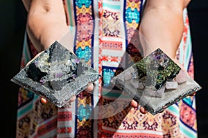 Beautiful shot of woman& x27;s hand holding two Orgonite Pyramid Generators