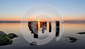 Beautiful shot of worn-out pier pillars on a body of water during sunset. Perfect for a wallpaper