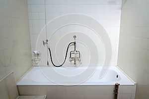 Beautiful shower bath with hot and cold water taps, white tile design wall, functionalism architecture