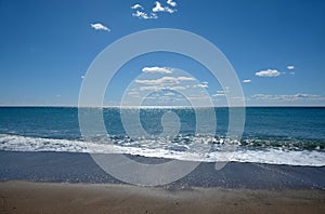 Beautiful sieside landscape with calm sea surf with waves and sun reflecton on water on skyline photo