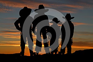 Beautiful silhouette of four young cowboys with a sunset background