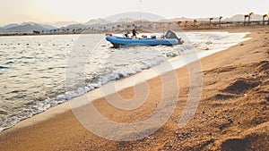 Beautiful silhouette of inflatable motor boat waving on the calm sea waves aginst sunset sky