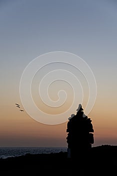 Beautiful silhouette landscape image of zen rock pile against vibrant peaceful sunset