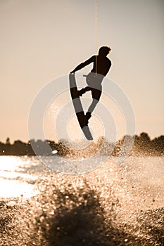 beautiful silhouette of wakeboarder athlete man jumping high making tricks in the air