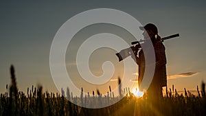 Silhouette of woman hunter. It stands in a picturesque place with a gun at sunset. Sports shooting and hunting concept