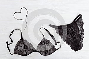 Beautiful silk lace bra and panty for woman. Black fashionable lingerie set and figure of heart from thin chain.