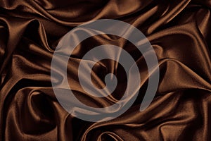Beautiful silk satin background. Chocolate brown shiny fabric with soft wavy folds. Elegant abstract background.