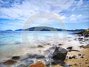 The beautiful silky smooth water waves and rocks on the sea shore.