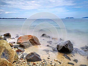 The beautiful silky smooth water waves and rocks on the sea shore.