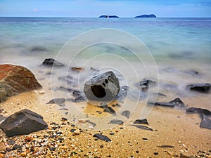 The beautiful silky smooth water waves and rocks on the sea shore.