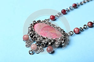 Beautiful silver necklace with rhodonite and tourmaline gemstones on blue background, closeup