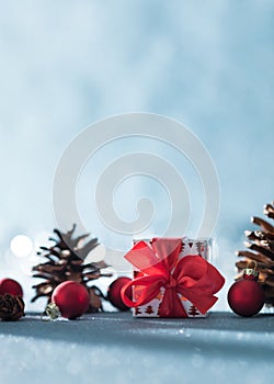 Beautiful simple Christmas background with copy space. Cute Christmas present, red ornaments and pine cones on blue background.