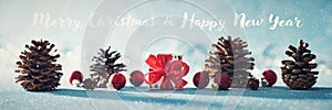 Beautiful simple Christmas banner with copy space. Cute Christmas present, red ornaments and pine cones on shiny blue background.