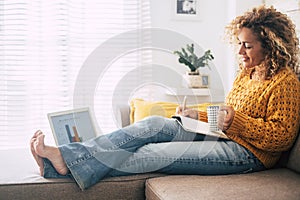 Beautiful single woman work at home with paper book and computer laptop together in old and modern job style concept - people in
