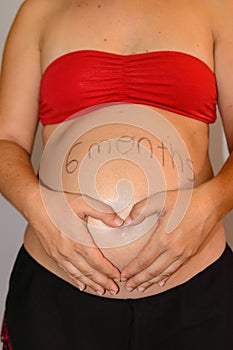 Beautiful six month pregnant woman showing her tummy drawing a heart on it with her hands. June 25, 2019. Madrid. Spain.