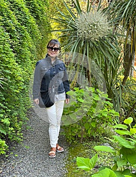 Beautiful sixty-five year-old Korean female tourist posing for a picture in the Garden of Villa Cipressi in Varenna.