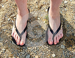 Beautiful Slates flip flops on women`s feet on the beach