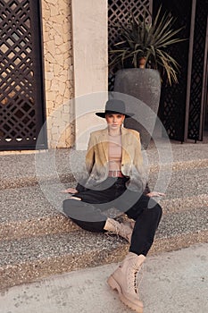 beautiful slavic woman with dark hair in casual clothes and black hat posing in the street of Limassol