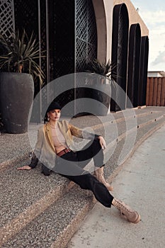 beautiful slavic woman with dark hair in casual clothes and black hat posing in the street of Limassol