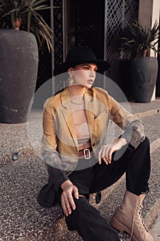 beautiful slavic woman with dark hair in casual clothes and black hat posing in the street of Limassol